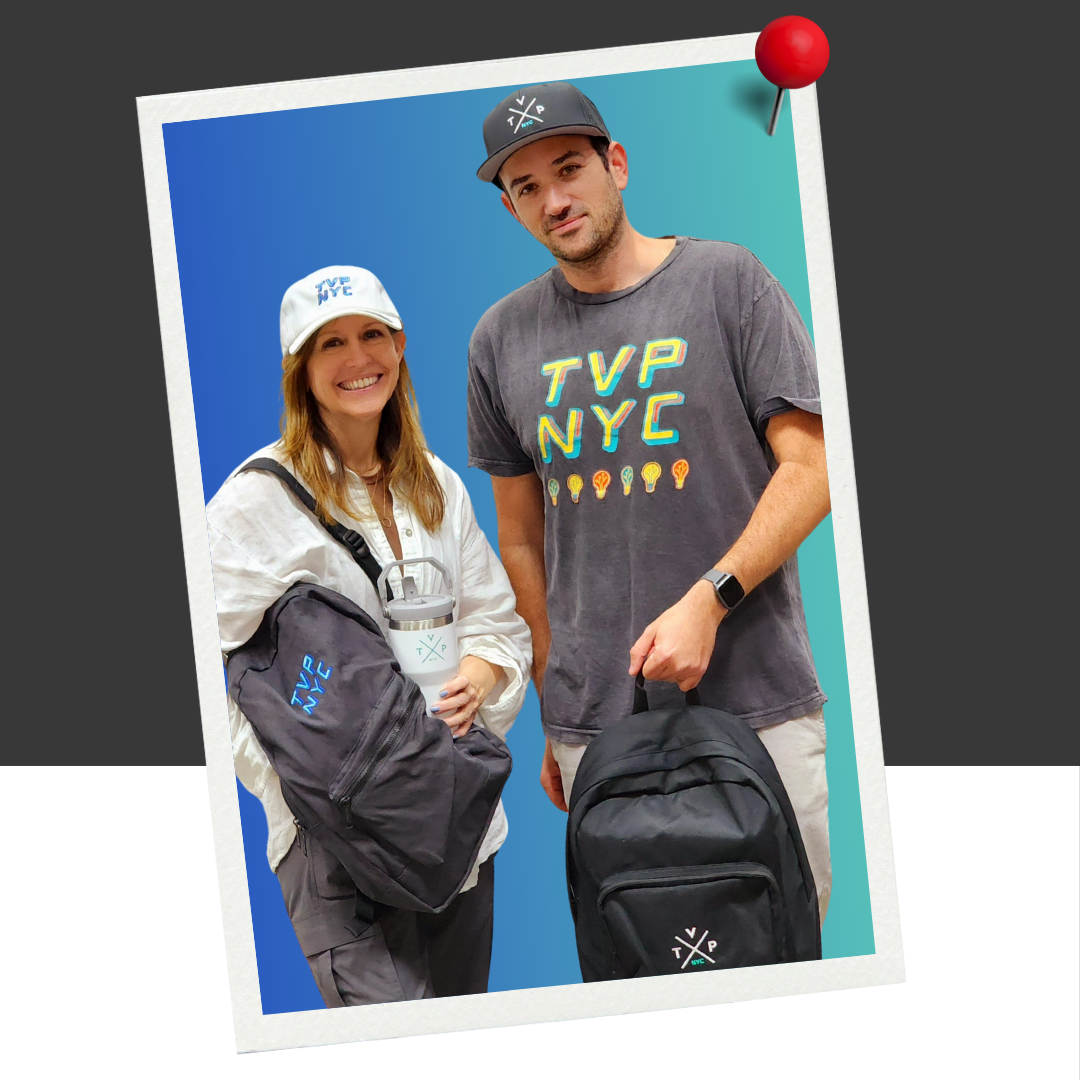 A photo of Lori Sochol and Omri Bojko from TVP NYC wearing TVP branded merch. Lori is wearing a branded trucker cap, branded hoodie, and branded backpack. Omri is wearing branded swag like a baseball cap, t-shirt, and backpack.