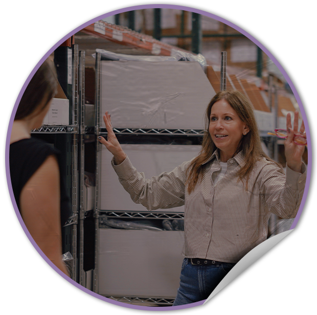 TVP fulfillment warehouse in NYC with a woman pointing at a rack with products.