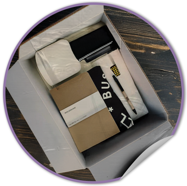 Open box containing TVP NYC promotional stationery items on a wooden surface