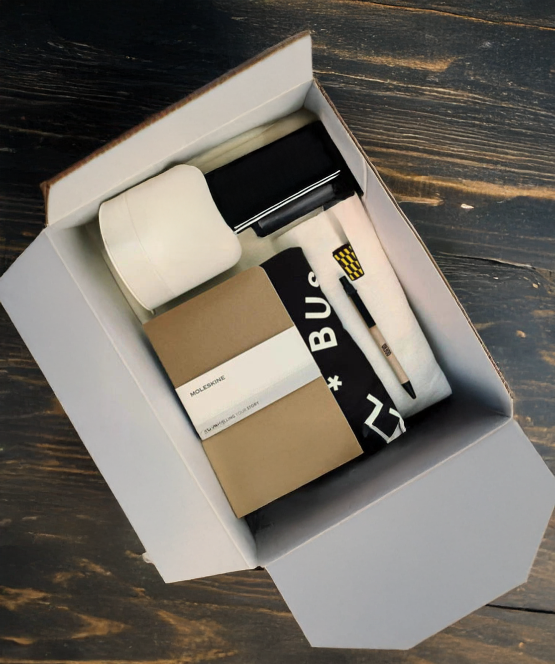 Set of TVP produced promo gift stationery items including a pen, notebook, and other office supplies in an open box on a wooden surface.