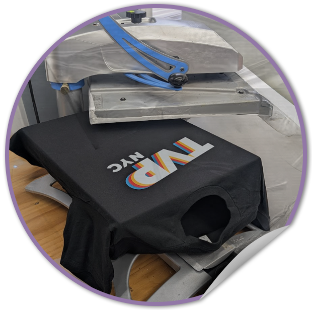 Black t-shirt with 'NYC TVP' design on a heat press machine.