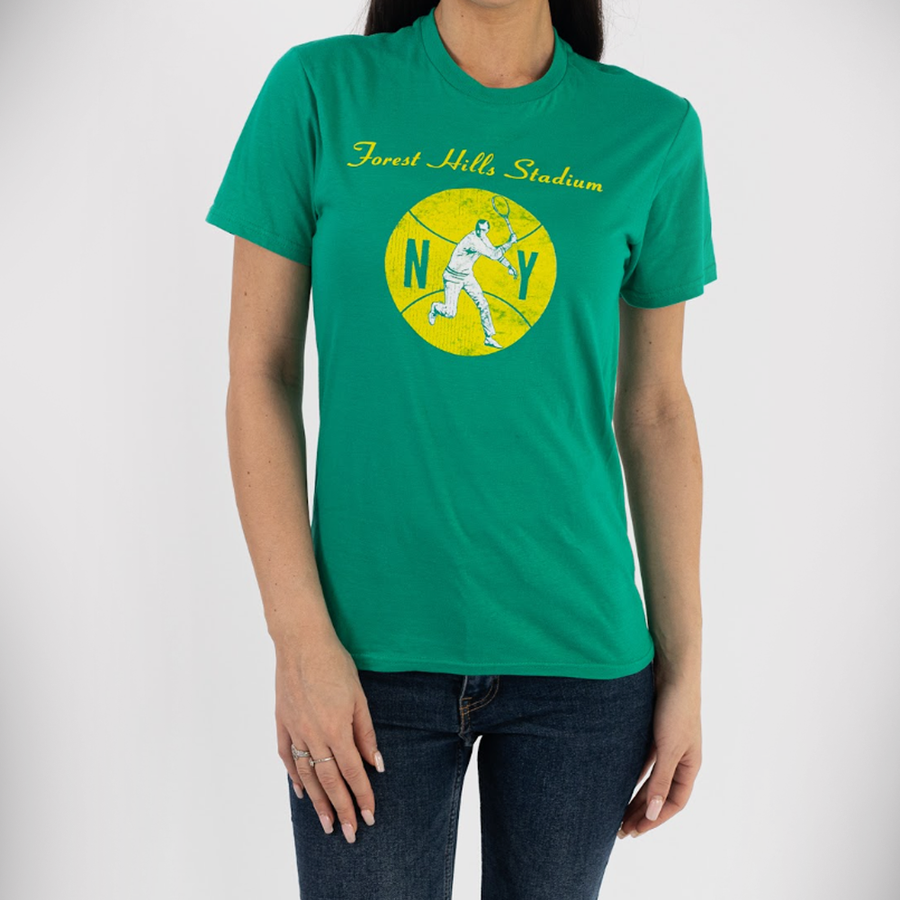 A woman wearing a bright emerald green t-shirt featuring a yellow circular graphic of a tennis player and "Forest Hills Stadium" in yellow script.
