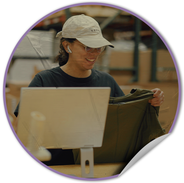 Person wearing a cap and earphones, holding a jacket in the TVP NYC warehouse.